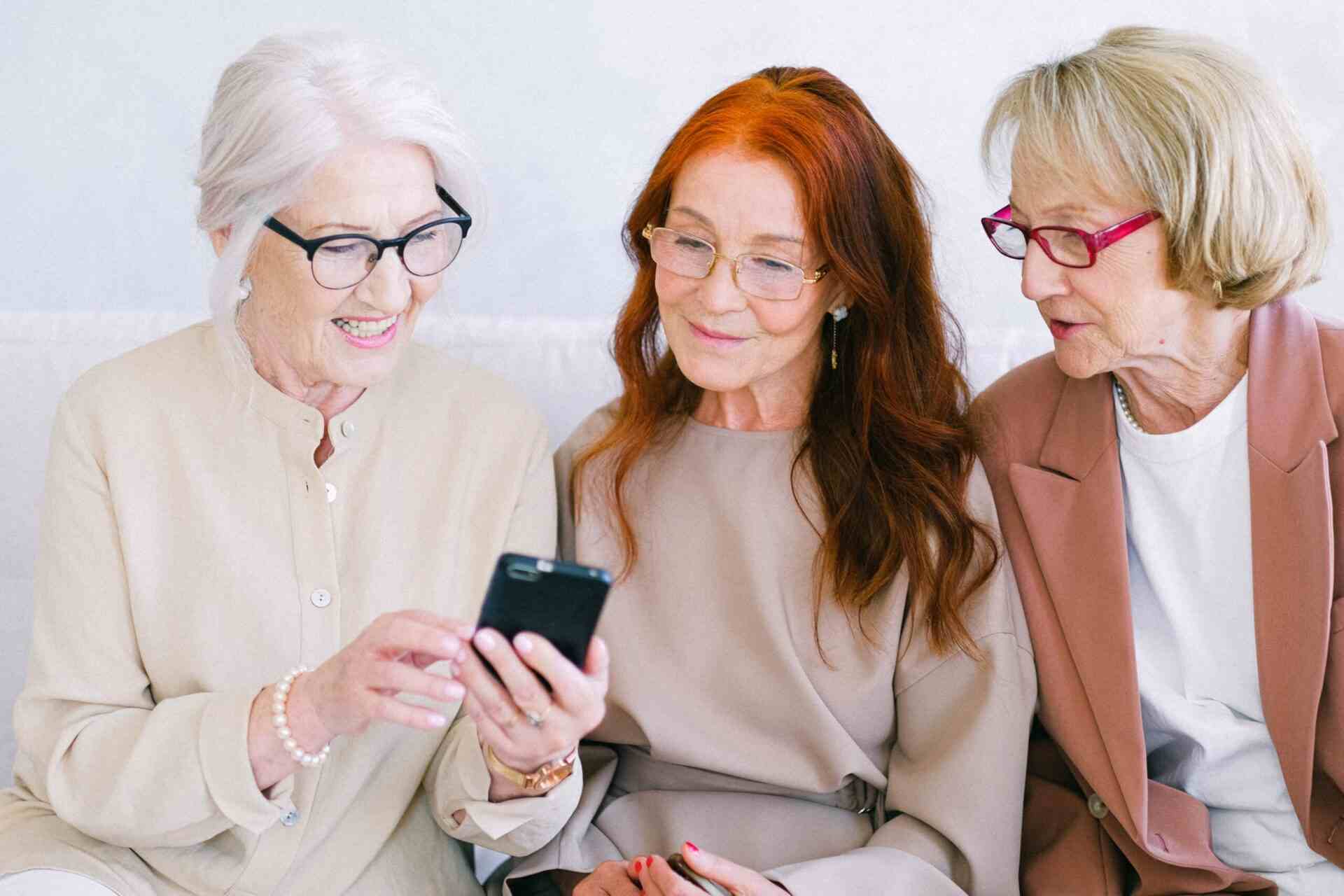 Drei ältere Frauen schauen gemeinsam auf ein Smartphone